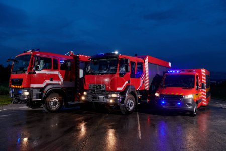 Foto de Un par de camiones de bomberos altamente modernos y de calidad iluminan la noche con sus luces giratorias, simbolizando la tecnología de vanguardia y la preparación de la flota de bomberos, listos para responder a - Imagen libre de derechos