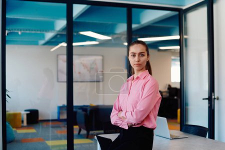 Photo for Portrait of a business woman in a creative open space coworking startup office with crossed arms. Successful businesswoman standing in office with copyspace. Associates work in the background. - Royalty Free Image