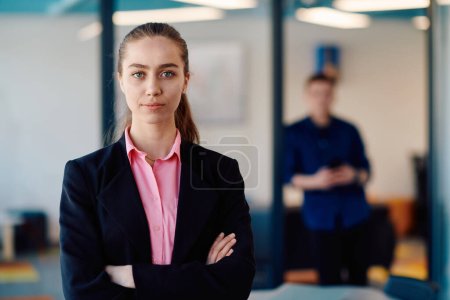 Photo for Portrait of a business woman in a creative open space coworking startup office with crossed arms. Successful businesswoman standing in office with copyspace. Associates work in the background. - Royalty Free Image
