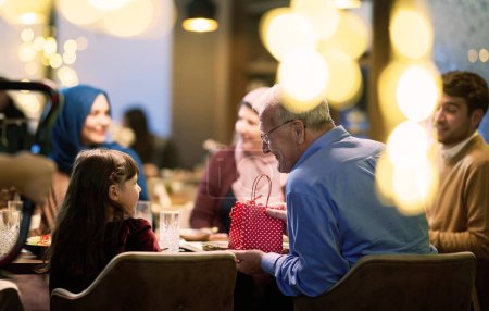 Téléchargez les photos : Une famille islamique européenne moderne et traditionnelle se réunit pour iftar dans un restaurant contemporain pendant la période de jeûne du Ramadan, incarnant l'harmonie culturelle et l'unité familiale au sein d'un - en image libre de droit