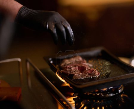 Primer plano, un chef profesional prepara expertamente un delicioso bistec utilizando técnicas de cocina modernas, mostrando la excelencia culinaria y la precisión en el arte de la cocina gourmet.