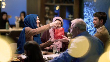 Téléchargez les photos : Les grands-parents arrivent à leurs enfants et petits-enfants se réunissant pour iftar dans un restaurant pendant le mois sacré du Ramadan, portant des cadeaux et partageant des moments d'amour, d'unité et - en image libre de droit
