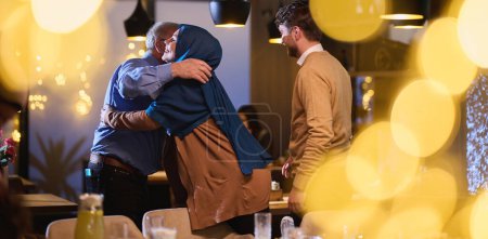 Téléchargez les photos : Les grands-parents arrivent à leurs enfants et petits-enfants se réunissant pour iftar dans un restaurant pendant le mois sacré du Ramadan, portant des cadeaux et partageant des moments d'amour, d'unité et - en image libre de droit