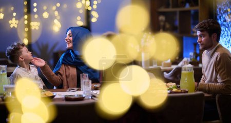 Téléchargez les photos : Dans un restaurant moderne, un couple islamique et leurs enfants attendent joyeusement leur repas iftar pendant le mois sacré du Ramadan, incarnant l'harmonie familiale et la célébration culturelle au milieu de la - en image libre de droit