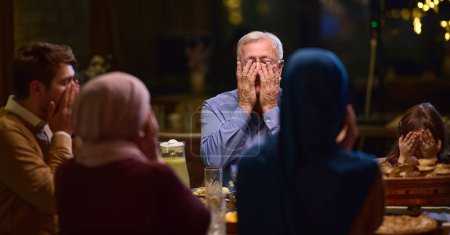 Dans un restaurant moderne, une famille islamique européenne se réunit pour iftar pendant le Ramadan, s'engageant dans la prière avant le repas, unissant tradition et pratiques contemporaines dans une célébration de