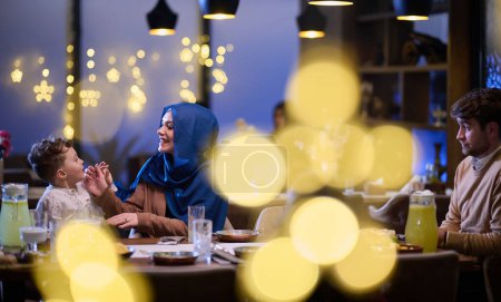 In einem modernen Restaurant warten ein islamisches Paar und ihre Kinder freudig auf ihr Iftar-Essen während des heiligen Monats Ramadan, das inmitten der heiligen Stätten familiäre Harmonie und kulturelles Feiern verkörpert.
