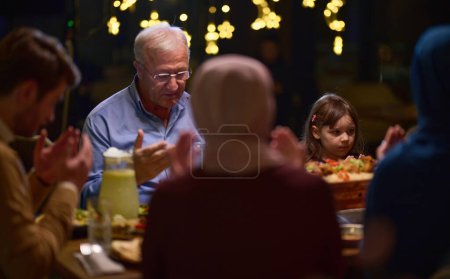 Téléchargez les photos : Dans un restaurant moderne, une famille islamique européenne se réunit pour iftar pendant le Ramadan, s'engageant dans la prière avant le repas, unissant tradition et pratiques contemporaines dans une célébration de - en image libre de droit