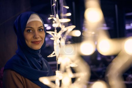 In einem modernen Restaurant-Ambiente macht eine Frau im Hijab ein Selfie neben leuchtenden Lichtern und präsentiert zeitgenössischen Stil und kulturelle Vielfalt in einer trendigen urbanen Umgebung