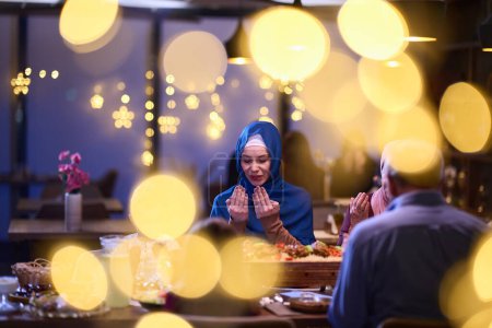 Photo for In a modern restaurant setting, a European Islamic family comes together for iftar during Ramadan, engaging in prayer before the meal, uniting tradition and contemporary practices in a celebration of - Royalty Free Image