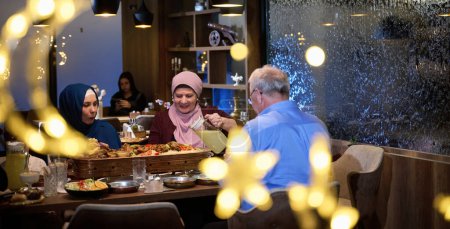 Photo for A modern and traditional European Islamic family comes together for iftar in a contemporary restaurant during the Ramadan fasting period, embodying cultural harmony and familial unity amidst a - Royalty Free Image