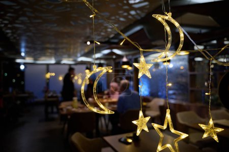In einem modernen Restaurant wird das Ambiente durch funkelnde islamische Ramadan-Dekorationen verändert, die eine festliche und kulturell reiche Atmosphäre schaffen.. 