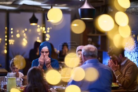 Foto de En un restaurante moderno, una familia islámica europea se reúne para iftar durante el Ramadán, participando en la oración antes de la comida, uniendo la tradición y las prácticas contemporáneas en una celebración de - Imagen libre de derechos