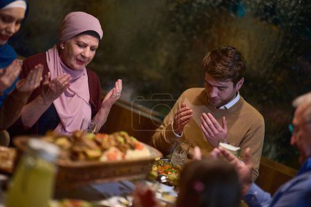 Foto de En un restaurante moderno, una familia islámica europea se reúne para iftar durante el Ramadán, participando en la oración antes de la comida, uniendo la tradición y las prácticas contemporáneas en una celebración de - Imagen libre de derechos