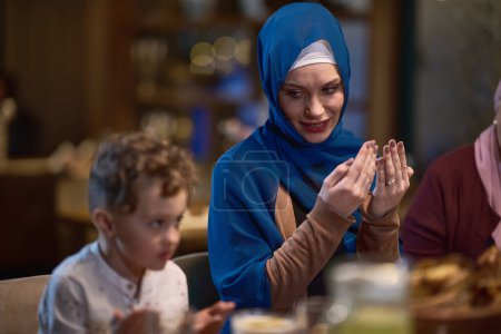 Téléchargez les photos : Dans un restaurant moderne, une famille islamique européenne se réunit pour iftar pendant le Ramadan, s'engageant dans la prière avant le repas, unissant tradition et pratiques contemporaines dans une célébration de - en image libre de droit