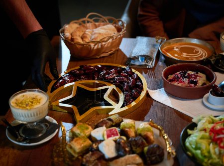 En esta cautivadora vista aérea, deliciosa comida adornada con decoraciones del Ramadán, incluyendo dátiles y carne, espera la llegada de una familia islámica europea, prometiendo un iftar festivo y sabroso
