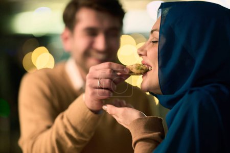 Photo for Islamic European couple shares laughter and enjoyment while savoring delicious pastries during iftar in the holy month of Ramadan, epitomizing joy, cultural celebration, and culinary delight. - Royalty Free Image
