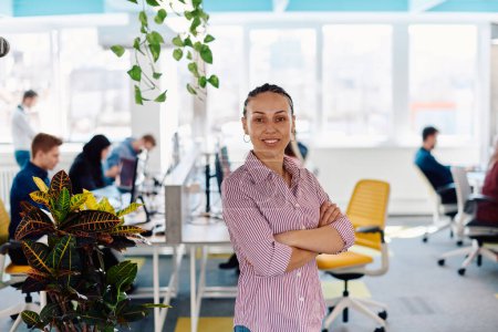 Photo for Portrait of young smiling business woman in creative open space coworking startup office. Successful businesswoman standing in office with copyspace. Coworkers working in background. - Royalty Free Image