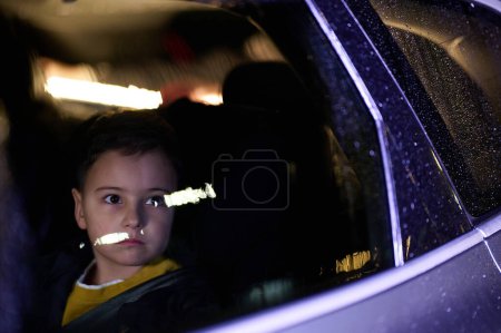 Ein kleiner Junge genießt eine Autofahrt durch das Fenster, während er die vorbeifahrende Landschaft beobachtet