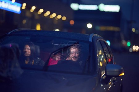 In the nighttime hours, a happy family enjoys playful moments together inside a car as they journey on a nocturnal road trip, illuminated by the glow of headlights and filled with laughter and joy.