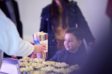 Photo for A young boy buys popcorn at the cinema before the start of the movie, his face lit up with excitement - Royalty Free Image