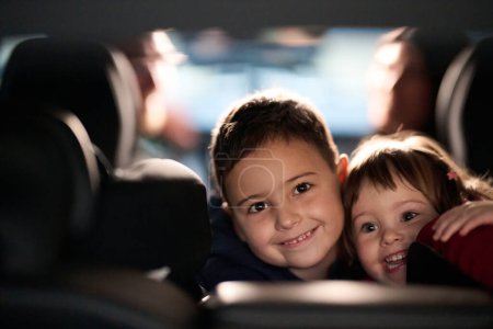 A young brother and sister enjoying a car ride together, immersed in the adventure of travel.