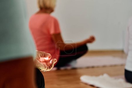 Téléchargez les photos : Dans cet espace ensoleillé, une main féminine âgée s'engage gracieusement dans diverses poses de yoga, incarnant l'essence du vieillissement actif, de la santé et de la paix intérieure.. - en image libre de droit