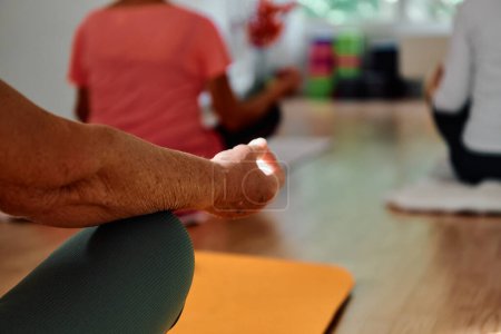 Photo for In this sunlit space, a senior womans hand gracefully engages in various yoga poses, embodying the essence of active aging, health, and inner peace. - Royalty Free Image