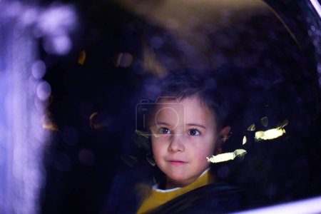 Foto de Un niño disfruta de un paseo en coche, capturado a través de la ventana, mientras observa el paisaje que pasa - Imagen libre de derechos