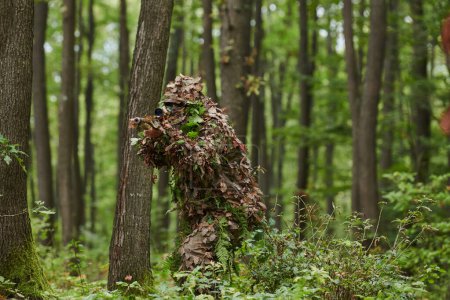 Un francotirador de élite altamente calificado, camuflado en el denso bosque, maniobra sigilosamente a través de terrenos forestales peligrosos en una misión encubierta y precisa. 