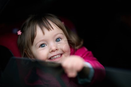 Photo for A young girl sits comfortably in a modern car seat, secured and ready for a family adventure on the road - Royalty Free Image