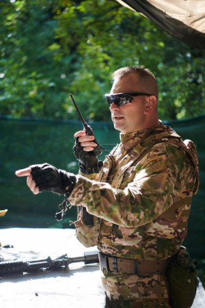 Téléchargez les photos : Un major militaire utilise une radio Motorola pour une communication transparente avec ses camarades lors d'une opération tactique, mettant en valeur le professionnalisme et la coordination stratégique. - en image libre de droit
