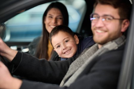 In den Nachtstunden genießt eine glückliche Familie verspielte Momente zusammen im Auto auf einer nächtlichen Roadtrip, beleuchtet vom Schein der Scheinwerfer und erfüllt von Lachen und Freude..