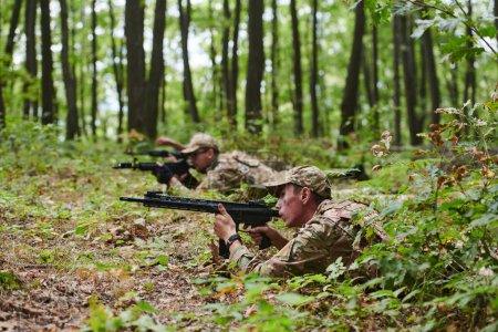 Téléchargez les photos : Des soldats d'élite manœuvrent furtivement à travers la forêt dense, camouflés en équipement spécialisé, alors qu'ils se lancent dans une mission militaire secrète et stratégique. - en image libre de droit