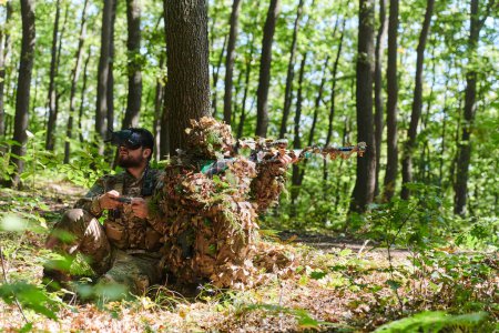 Ein erfahrener Scharfschütze und ein Soldat, der eine Drohne mit VR-Brille bedient, verfolgen die Militäraktion, während sie im Wald versteckt sind. 