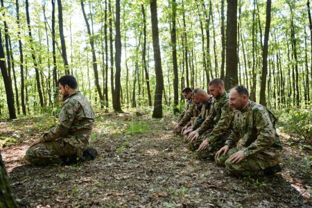 Un groupe de soldats dévoués s'engage dans la prière islamique dans les conditions difficiles et périlleuses d'une opération militaire dans des zones boisées denses. 