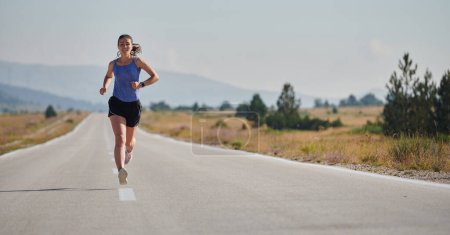 Photo for An athletic woman finds freedom and joy in a healthy lifestyle, running through a beautiful road trail at sunrise. - Royalty Free Image