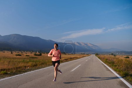 Photo for A resolute and motivated athlete running confidently into the sunrise, epitomizing determination and empowerment in her early morning run. - Royalty Free Image