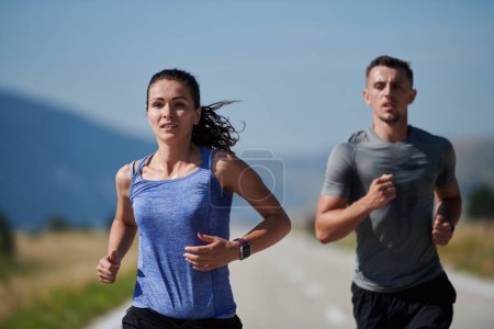 Photo for A couple runs through a sun-dappled road, their bodies strong and healthy, their love for each other and the outdoors evident in every stride. - Royalty Free Image