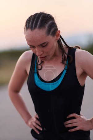 Photo for A close-up captures the raw dedication of a female athlete as she rests, sweat glistening, after a rigorous running session, embodying the true spirit of perseverance and commitment to her fitness - Royalty Free Image