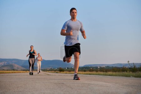 Photo for A group of friends maintains a healthy lifestyle by running outdoors on a sunny day, bonding over fitness and enjoying the energizing effects of exercise and nature. - Royalty Free Image
