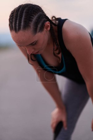 A close-up captures the raw dedication of a female athlete as she rests, sweat glistening, after a rigorous running session, embodying the true spirit of perseverance and commitment to her fitness