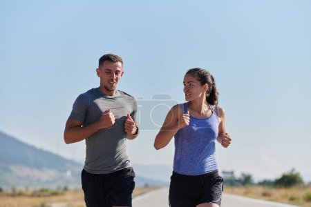 Un couple traverse une route ensoleillée, leur corps fort et en bonne santé, leur amour les uns pour les autres et le plein air évident à chaque pas. 