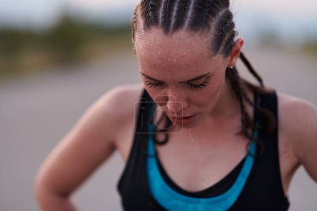 Photo for A close-up captures the raw dedication of a female athlete as she rests, sweat glistening, after a rigorous running session, embodying the true spirit of perseverance and commitment to her fitness - Royalty Free Image