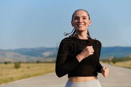 Téléchargez les photos : Une femme sportive trouve la liberté et la joie dans un mode de vie sain, courant à travers un beau sentier routier au lever du soleil. - en image libre de droit