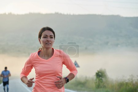 Foto de Una mujer atlética encuentra libertad y alegría en un estilo de vida saludable, corriendo a través de un hermoso sendero al amanecer. - Imagen libre de derechos