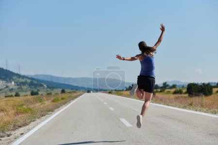Photo for In a powerful display of triumph and commitment to her sport, an athlete leaps into the air, symbolizing success and dedication in her running journey. - Royalty Free Image
