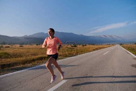 Foto de Una atleta resuelta y motivada corriendo con confianza hacia el amanecer, personificando la determinación y el empoderamiento en su carrera matutina. - Imagen libre de derechos