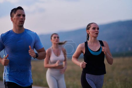 Photo for A diverse group of runners finds motivation and inspiration in each other as they train together for an upcoming competition, set against a breathtaking sunset backdrop. - Royalty Free Image