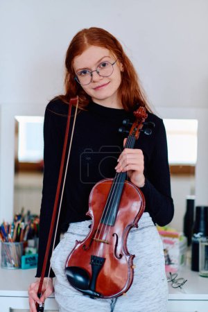 A stunning redhead musician exudes elegance as she poses with her violin, embodying both grace and musical prowess.