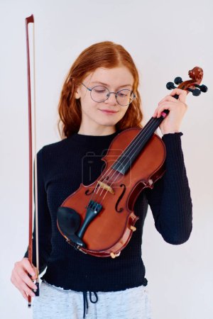 Téléchargez les photos : Une superbe musicienne rousse respire l'élégance en posant avec son violon, incarnant à la fois la grâce et les prouesses musicales. - en image libre de droit